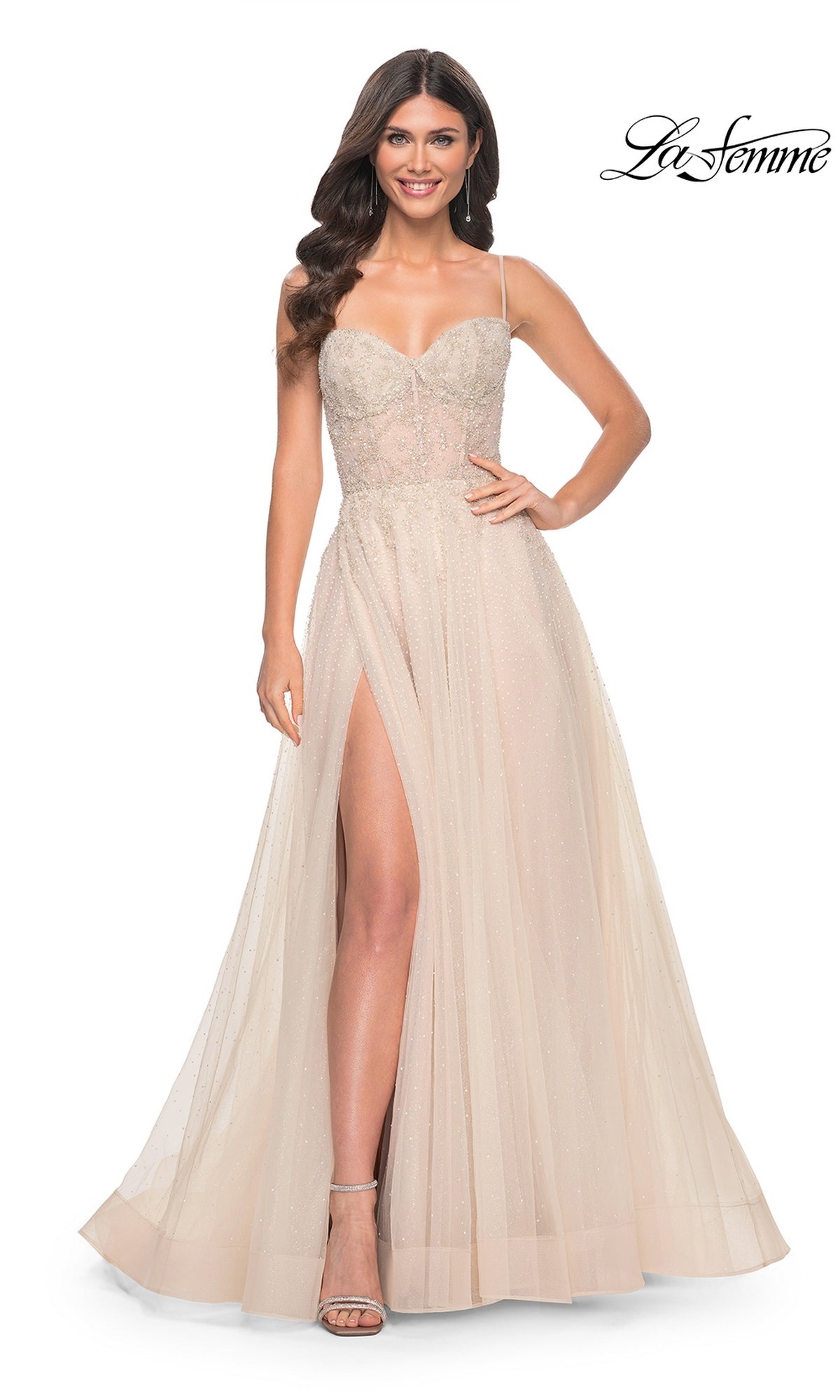 A woman models the La Femme Champagne Long A-Line Prom Dress 32271, featuring a sleeveless sheer bodice, thin straps, and a high slit, set against a white background with the